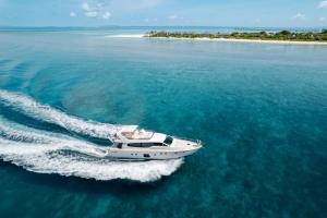 a white boat in the water near an island at Hideaway Beach Resort & Spa in Dhidhdhoo