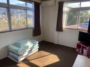 Zimmer mit 2 Fenstern, einem Bett und einem TV in der Unterkunft Guest House Iwato in Takachiho