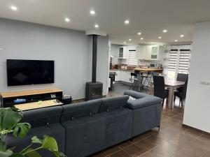 ein Wohnzimmer mit einem schwarzen Sofa und einem TV in der Unterkunft Maison rénovée à ceton dans la région du perche en basse Normandie in Ceton