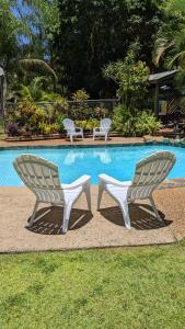 two white chairs sitting next to a swimming pool at Gumnut Glen Cabins in Yeppoon