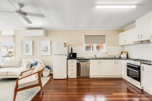 a kitchen with white cabinets and a white couch at Light & Bright! 3 Bedroom Cottage, East Toowoomba! in Toowoomba