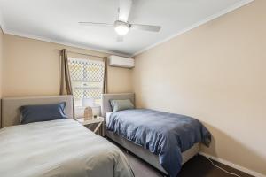 1 dormitorio con 2 camas y ventana en Light & Bright! 3 Bedroom Cottage, East Toowoomba!, en Toowoomba