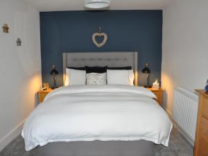 a bedroom with a white bed with a blue wall at Hafan in Llanerfyl