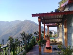 a woman sitting on a porch with a view of a mountain at Neer Ganga Resorts in Rishīkesh