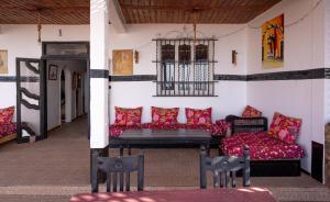 una sala de estar con sofás rojos y una jaula para aves. en Auberge Sable D'Or en Sidi Ifni