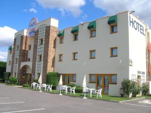 un hôtel avec des tables et des chaises blanches en face dans l'établissement Kimotel Epône-Flins, à Épône