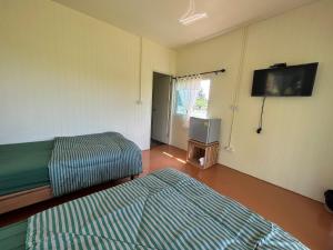 Zimmer mit 2 Betten und einem Flachbild-TV in der Unterkunft Rak Suan Homestay รักสวนโฮมสเตย์ in Khao Lak
