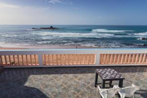 uma varanda com uma mesa e cadeiras e o oceano em Auberge Sable D'Or em Sidi Ifni