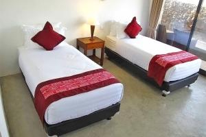 two beds with red pillows in a room at Balibo Fort Hotel in Balibo