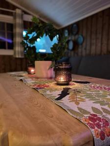 uma mesa de madeira com uma vela em cima em Koselig hytte med uteplas ved Hallingdalselva em Al