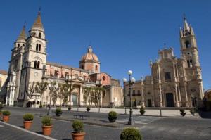 a large building with two towers and potted plants at Come In Sicily La Pietra Monaca in Acireale