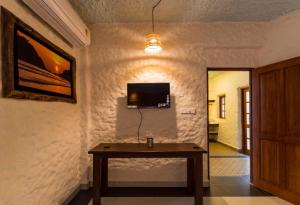 Avontade Suites في أنجونا: غرفة مع طاولة وتلفزيون على الحائط