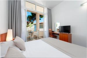 een slaapkamer met een bed, een bureau en een televisie bij Hotel Vis in Dubrovnik