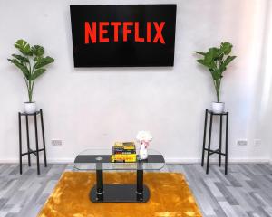 a living room with a table and a netflix sign on the wall at I Love London! A STUNNING 2Bed Home Sleeps 1-4! in Thamesmead