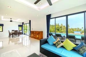 an open living room with a blue couch and a dining room at Sea VIEW POOL Villa - 8 peoples- Private Pool - Beautiful garden in Ban Bang Po
