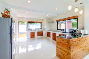 a large kitchen with white floors and wooden cabinets at Sea VIEW POOL Villa - 8 peoples- Private Pool - Beautiful garden in Ban Bang Po