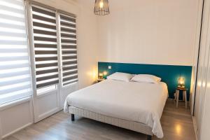 een slaapkamer met een wit bed met een blauw hoofdeinde bij BUGEAUD #2 - Grande Terrasse - 2 chamb in Brive-la-Gaillarde