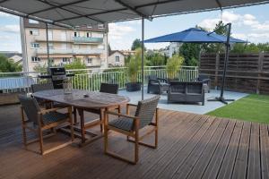 een houten terras met een tafel en stoelen en een parasol bij BUGEAUD #2 - Grande Terrasse - 2 chamb in Brive-la-Gaillarde