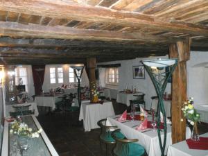 un restaurante con mesas y sillas blancas y techos de madera en Altes Badhaus en Eberbach