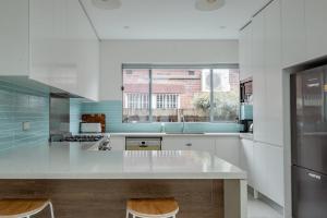 a kitchen with a counter with two chairs in it at Elegant Federation Home Near The Airport in Sydney