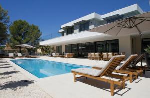 ein Haus mit einem Pool mit Stühlen und einem Sonnenschirm in der Unterkunft VILLA SP SUITES SANTA PONSA in Santa Ponsa