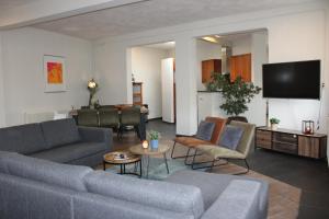Hotel 't Peperhuys في كاتْسهوفيل: غرفة معيشة مع أريكة وكراسي وتلفزيون