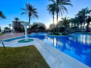 a swimming pool with palm trees in a resort at SUNSET Beach in El Campello