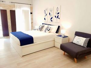 a white bedroom with a bed and a chair at Home Giulia Best Vacation Ever in Cagliari