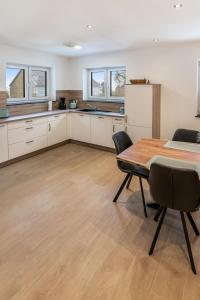 a kitchen with white cabinets and a table and chairs at Ferienwohnung Eifelhöhe Reger in Hellenthal