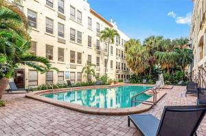 una piscina en un patio con sillas y un edificio en Renovated studio in the heart of Palm Beach with free valet parking, en Palm Beach