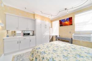 Cet appartement comprend une chambre avec un lit et une cuisine avec des placards blancs. dans l'établissement Renovated studio in the heart of Palm Beach with free valet parking, à Palm Beach