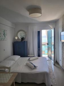 a white bedroom with two beds and a balcony at Apartment Milena in Drasnice