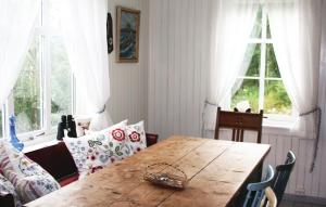 a dining room with a wooden table and two windows at Holiday Home Flekke Eldevik Ii in Flekke