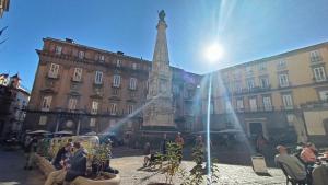 a statue in the middle of a city with people at Famme sta cuiete appartamento Napoli centro in Naples