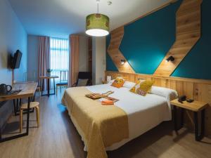 Habitación de hotel con cama y pared azul en Hotel San Miguel en Gijón