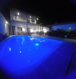 a large blue swimming pool in front of a house at night at Casa Versel Trancoso in Trancoso