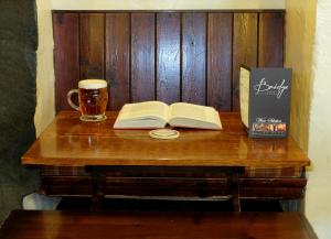 una mesa con un libro abierto y una taza de cerveza en Bridge Hotel, en Buttermere