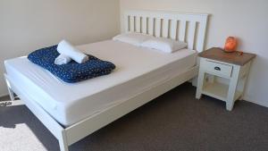 um quarto com uma cama branca e uma mesa lateral em Homestay, millions dollars view at Mount Pleasant em Christchurch