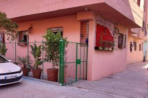 a pink house with a green gate in front of it at proche aéroport, idéal pour travailler in Marrakesh