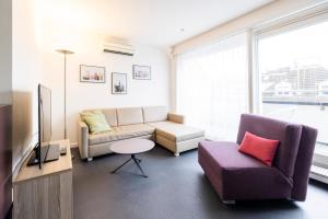 ein Wohnzimmer mit einem Sofa und einem Stuhl in der Unterkunft EMA House Serviced Apartments Seefeld in Zürich