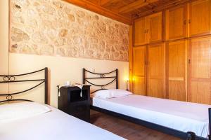 2 camas en un dormitorio con paredes de madera y suelo de madera en Katouna Holiday House, en Katouna