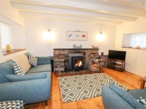 a living room with a fireplace and a blue couch at Little Barn Cottage in Newport Pembrokeshire