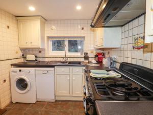 a kitchen with a stove and a washing machine at Little Barn Cottage in Newport Pembrokeshire +7 photos