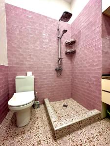 baño con aseo y pared de ladrillo rosa en Mariko's Apartment, en Tiflis