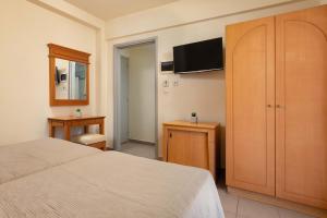 a bedroom with a bed and a cabinet and a television at City Plus Rhodes Hotel in Rhodes Town