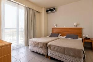 Habitación de hotel con 2 camas y ventana en City Plus Rhodes Hotel, en Rodas