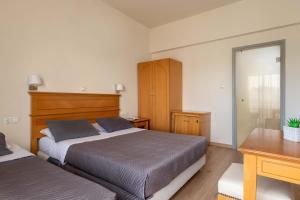 a bedroom with two beds and a desk and a mirror at City Plus Rhodes Hotel in Rhodes Town