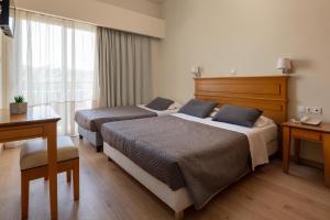 a hotel room with two beds and a desk at City Plus Rhodes Hotel in Rhodes Town