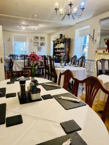 uma sala de jantar com uma mesa com mesas e cadeiras brancas em Newcastle Arms Hotel em Coldstream