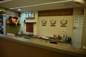 einen Tresen in einem Restaurant mit Uhren an der Wand in der Unterkunft Hotel Diamora Residency in Thane